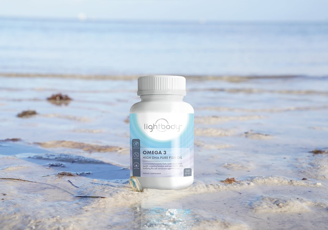 A picture capturing a Lightbodylabs omega-3 supplement bottle positioned on a sandy beach under a clear sky, serving as a visual guide on how to compare omega-3 supplements.