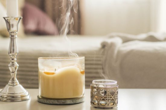 A decorative candle burning out on a dresser in the bedroom.