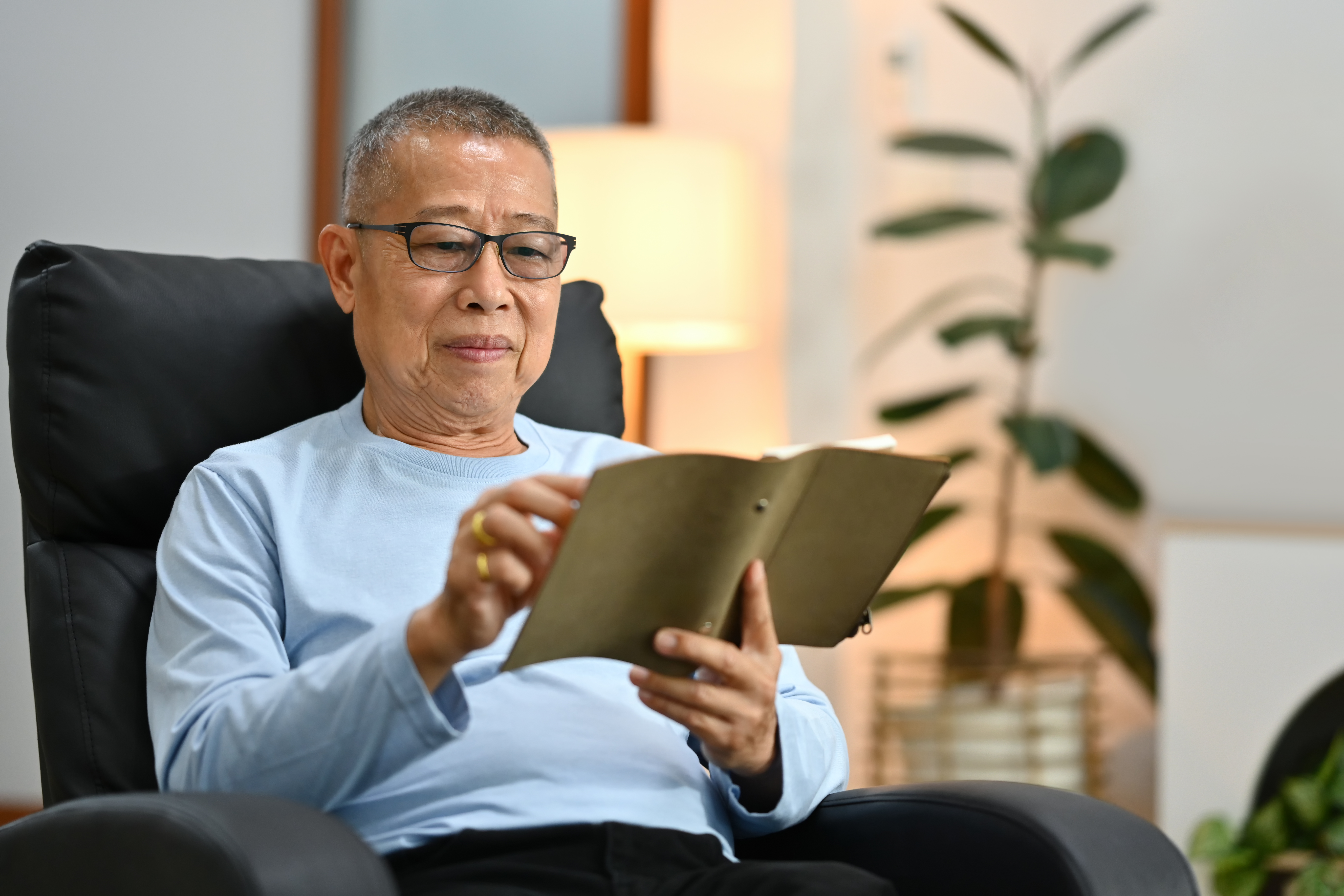 An older person wearing glassess skimming through book, finding calm in simple pleasures – a picture illustrating the blog about physical signs of stress in the older person.